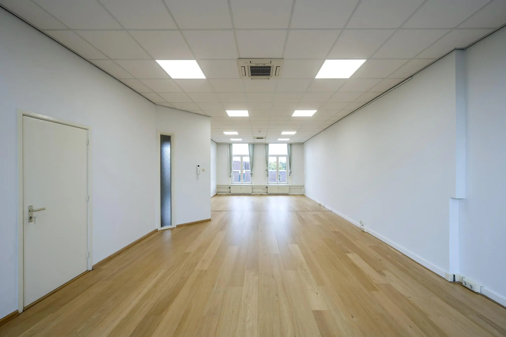 Licht en ruim leeg kantoor met houten vloer aan de Nieuwe Gracht.